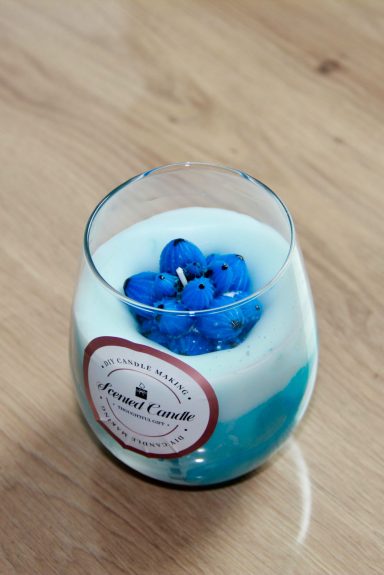 Ein Glas mit einer blauen Kerze und einer Schicht in Cremefarbe.